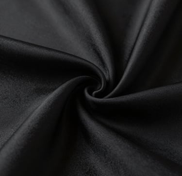 Macro detail of high-quality black silk texture draped elegantly. The lighting is soft but dramatic, emphasizing the craftsmanship and luxury of the material. Minimalist aesthetic following the #0F0F0F and #333333 color scheme.