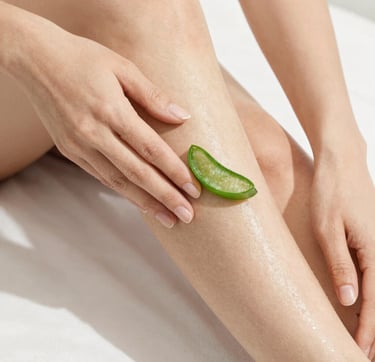 A person applying a fresh slice of natural aloe vera leaf to a smooth leg for skin hydration and soothing care.