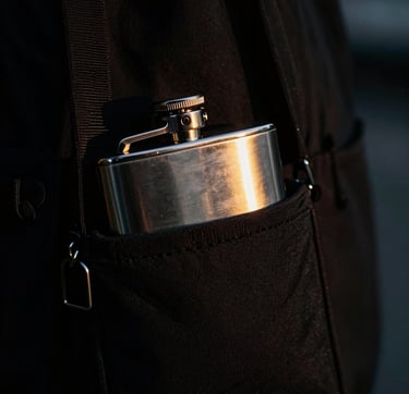 Tight macro detail of a sleek black bottle bag holding a metal flask, neon gold highlights, high contrast, 35mm