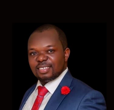 Professional headshot of a smiling man in a blue suit and red tie with a red lapel flower.