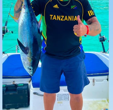 Happy tourist in Zanzibar proudly holding a big tropical fish after an exciting fishing trip on the Indian Ocean