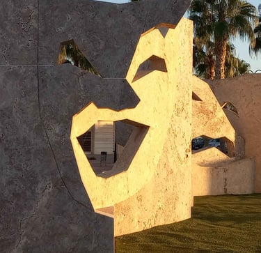 Large stone theater mask sculptures with palm trees in the golden hour sunlight.