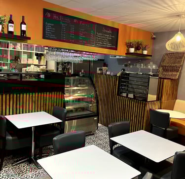 a restaurant with tables and chairs and a counter displaying cakes and pastries