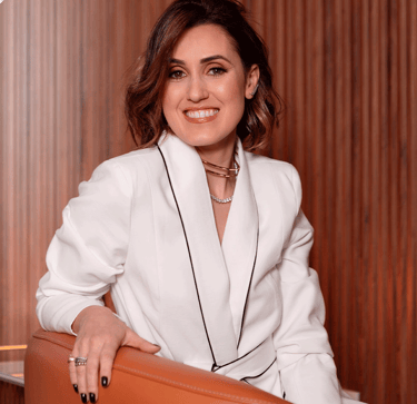 Bruna, mulher com vestes sociais olhando com um sorriso