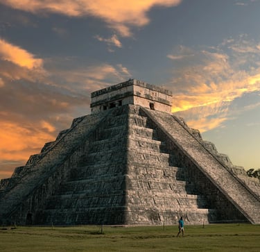 Maravilla del mundo, la pirámide maya de Chichén Itzá, al atardecer bajo un cielo naranja dramático 