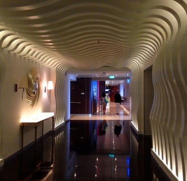 Un pasillo de hotel de lujo moderno con un techo escultórico ondulado blanco y paneles de pared 