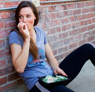 A woman eating some healthy food from a togo container.  