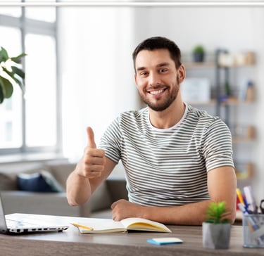 a man sitting at a desk with a laptop and a notebook
