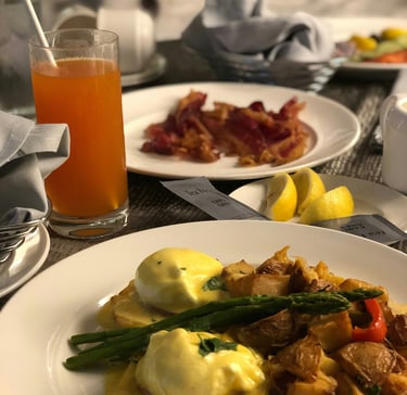 Hotel room service breakfast. Orange, bacon,potato, asparagus,lemon on plate.Guest Experience