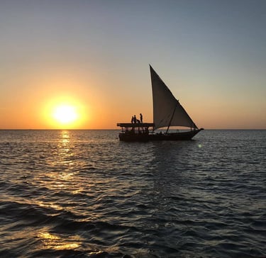 Tourists enjoying a magical sunset on a traditional dhow cruise in Zanzibar, Tanzania.