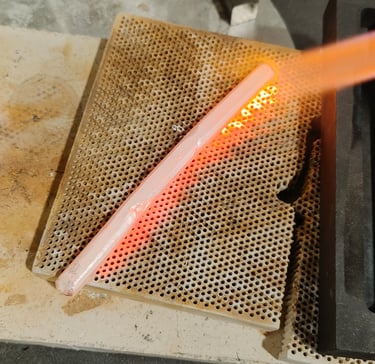 Hot silver piece being quenched in water after heating.