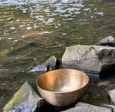 Klangschale steht behutsam am Wasser.