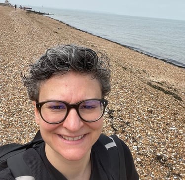 a woman with glasses and a backpack on a beach