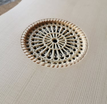Close-up of an intricate hand-carved rosette covering the soundhole of a Renaissance vihuela