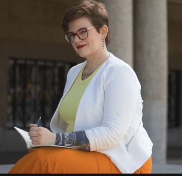 ein Foto von Swana Schuchmann, mit Notizbuch und Stift. Sie schreibt.