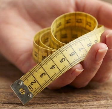 Main de femme tenant un mètre ruban pour mesurer la taille d’une bague