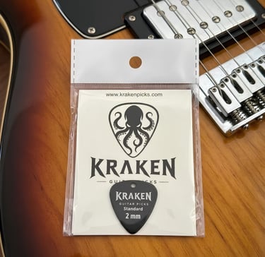 Kraken black guitar picks 2mm standard in packaging on a sunburst electric guitar body.