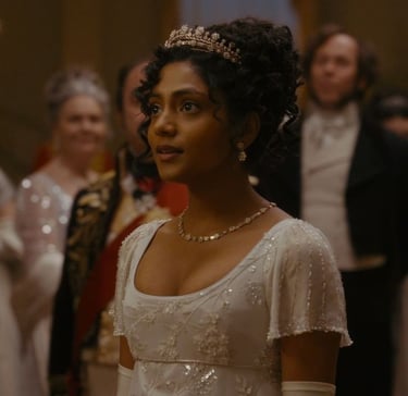 Edwina Sharma usando um vestido de baile branco e tiara em Bri