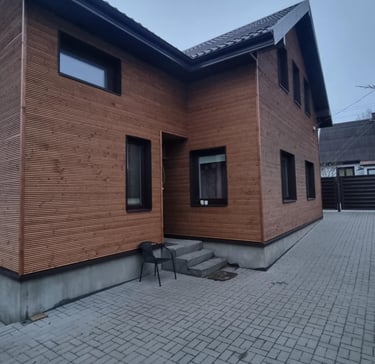 Namo fasadas renovuotas padengiant jį horizantaliomis medinėmis lentelėmis.