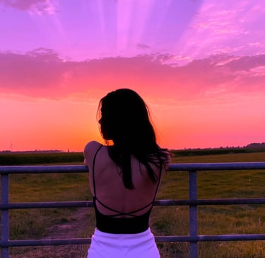 woman watching sunset with soft aesthetic sky, personal style inspiration and curated fashion lifest