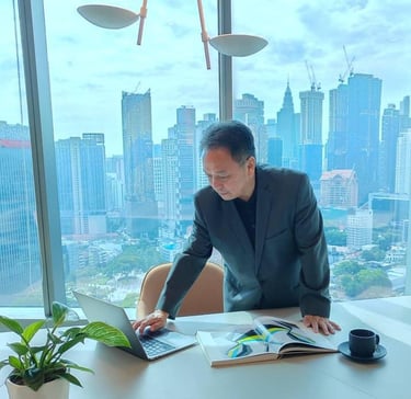 Professional businessman in a suit working on a laptop in a high-rise office with a city skyline view.