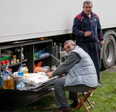 Reinhard Mokros: Zwei LKW-Fahrer bereiten sich an einem Sonntag ein Mittagessen an ihrem LKW.