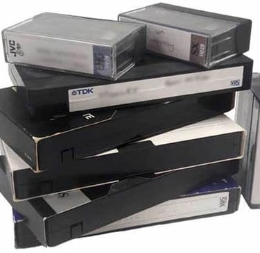 A stack of vintage VHS tapes and small video cassettes for analog media conversion.