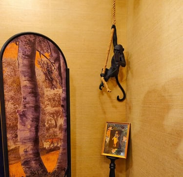 Black monkey hanging lamp with rope in a room featuring jungle themed wall art and decor.