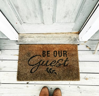 doormat at the door with Be Our Guest sign. Market positioning for tourism businesses with Timea
