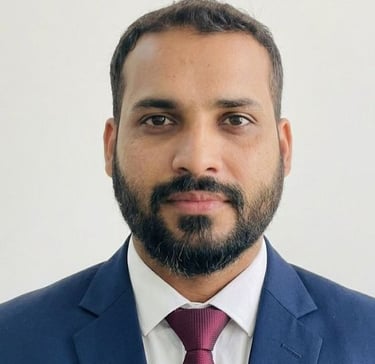 Professional headshot of a bearded man wearing a blue suit and maroon tie for a corporate profile.
