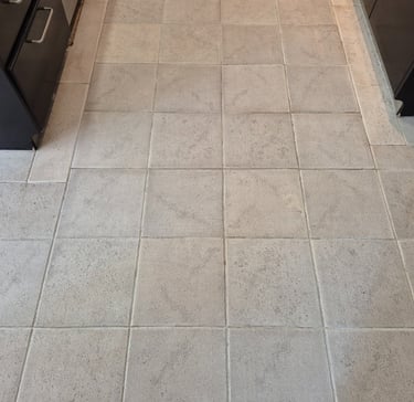 Light gray square ceramic floor tiles in a kitchen after laser cleaning