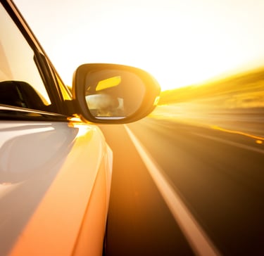 Auto siendo conducido en una amplia carretera en el atardecer