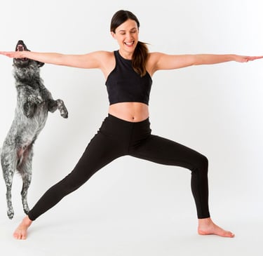a woman in a black top and leggings and a dog standing in front