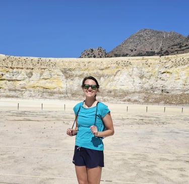 a woman in a blue shirt and sunglasses standing in a desert