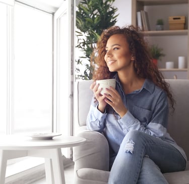 a woman sitting on a couch with a cup of coffee after she's had anxiety relief