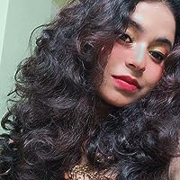 An attractive young woman with long, dark, wavy hair. Her head is tilted to one side as she looks at the camera