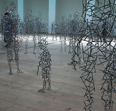 a group of people standing in a room with many metal sculptures
