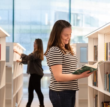 Lehdistökuva tytöistä lukemassa kirjaa Oodi kirjastossa Helsingissä