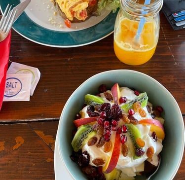 a bowl of fruit salad with a glass of orange juice