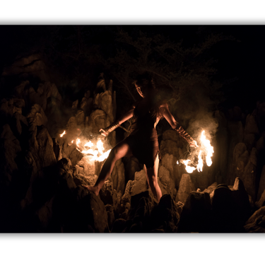 a woman in a black dress is holding a fire