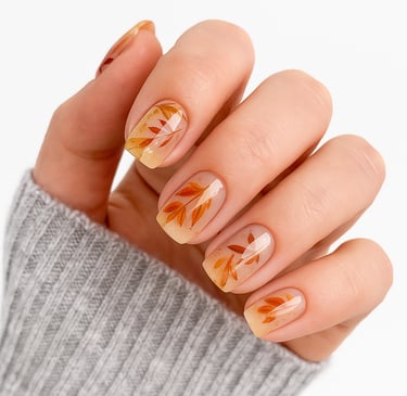 a women's hand with autumn leaf press on nails an a grey sweater