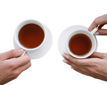 A top-down view of two people holding white ceramic cups of hot black tea over saucers.