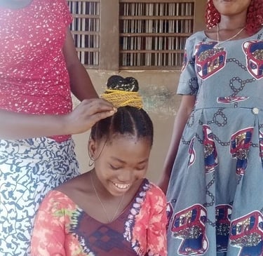 Une fille qui se fait coiffer par une étudiante du centre d'éducation alternatif de Zè