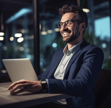 Business man at desk in front of laptop smiling
