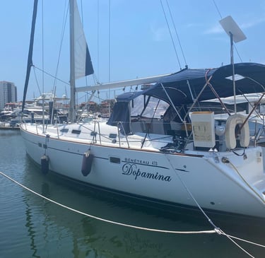 a sailboat docked at a marina with a boat in the water