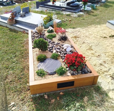 Monument funéraire en bois avec aménagement de galets de galets et fleurs rouges