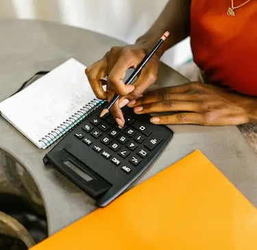 Femme estimant un montant sur une calculette, avec un crayon de papier noir dans la main