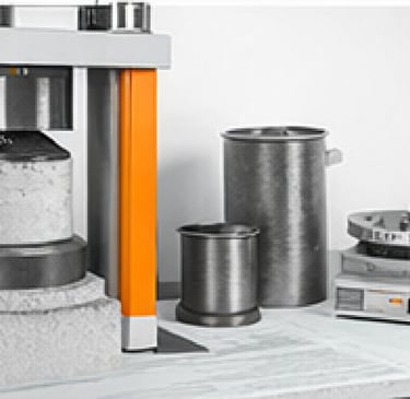 Prensa hidráulica y moldes para ensayos de resistencia de hormigón.