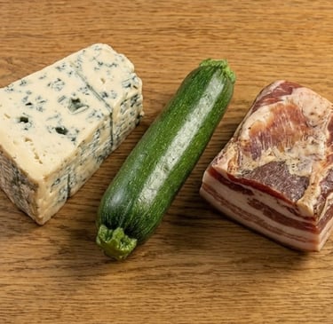 Fresh blue cheese wedge, green zucchini, and cured pancetta meat on a wooden table.
