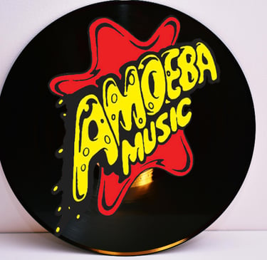 A black vinyl record featuring the yellow and red Amoeba Music logo sticker on the center label.